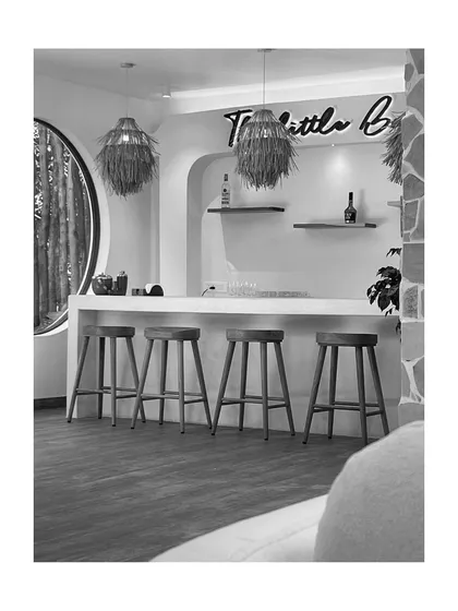 The bar area, presented in black and white, draws attention to the clean lines of the counter, the simple elegance of the stools, and the unique texture of the pendant lights.