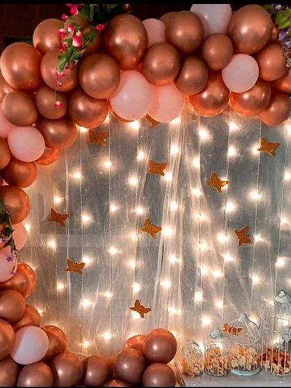 This rose gold balloon arch against a fairy-lit backdrop is perfect for adding a touch of warmth and sparkle to any event. The golden butterflies add a whimsical and delicate detail.