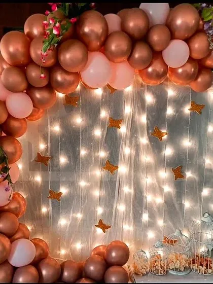 A beautiful ring backdrop featuring rose gold and pink balloons, with a curtain of fairy lights. This setup is perfect for creating a magical and romantic photo corner at any birthday celebration.