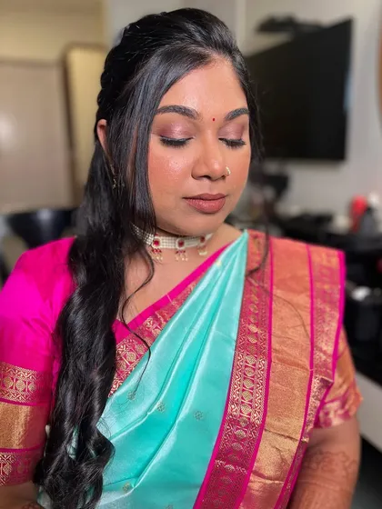 A soft and pretty engagement look. The makeup features pink tones on the eyes and lips, complementing her turquoise saree.