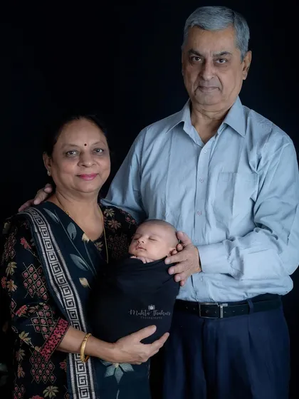 A beautiful portrait capturing three generations of family love, with grandparents and parents surrounding their precious newborn.