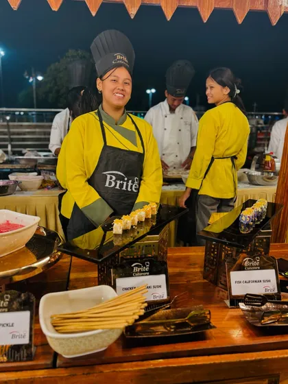 My smiling chef at the sushi station, presenting a platter of freshly prepared rolls, showcasing the friendly service I provide.