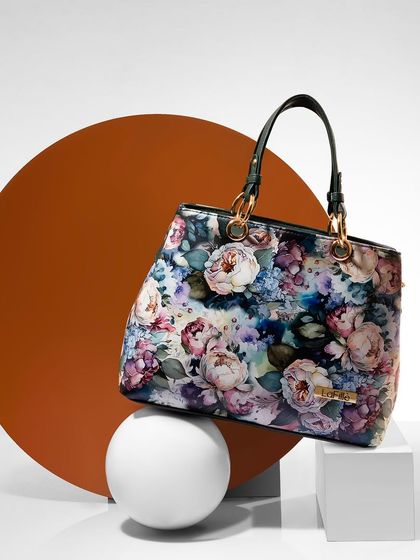 A floral-print handbag styled with geometric props. The contrast between the organic pattern of the bag and the clean, solid shapes makes for a visually dynamic photo.