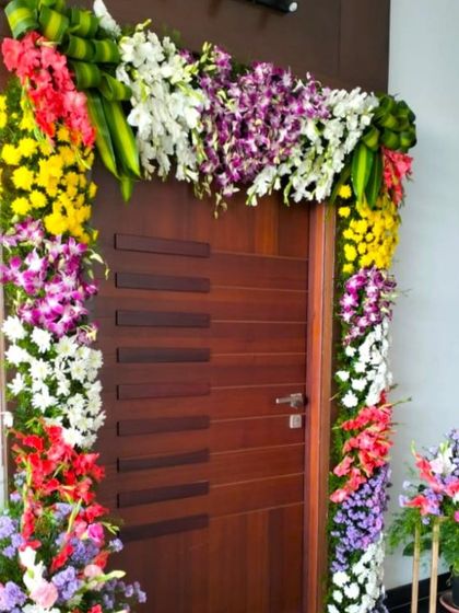 A housewarming flower decoration for a modern home. The door is framed with an arch of orchids and other exotic flowers for a contemporary look.