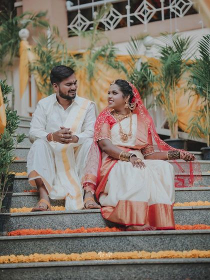 The couple seated on steps adorned with marigold flowers, sharing a quiet moment during their wedding day.