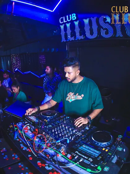 A focused moment at the decks at Club Illusions, with the club's signature blue lighting setting the mood.