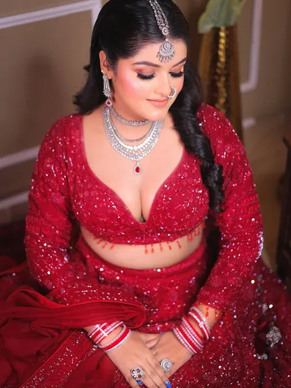 A downward-looking pose that beautifully displays the neckline of the blouse and the intricate necklace.