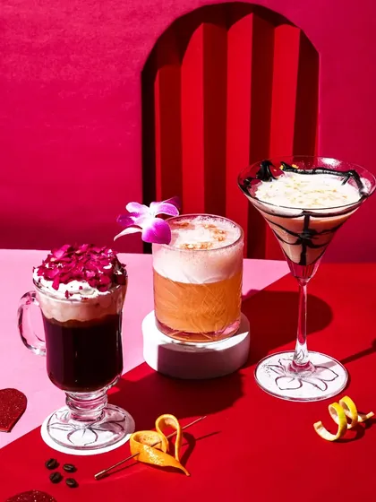 A trio of Valentine's Day special cocktails, including a creamy martini, a frothy sour, and a dramatic rose-petal coffee. The red and pink theme creates a romantic and festive mood.
