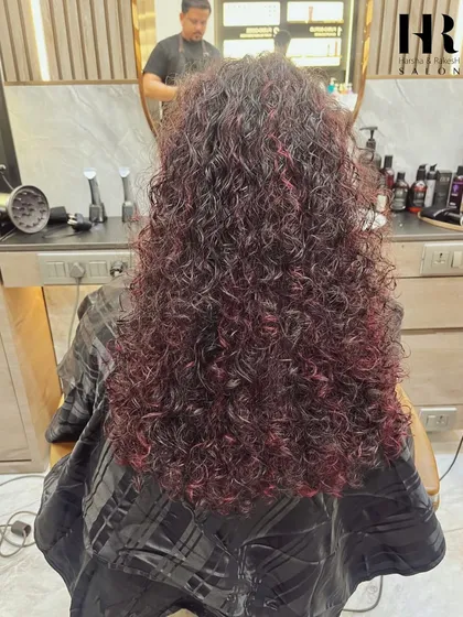 A fun and vibrant look with curly hair colored in a beautiful shade of burgundy. This shows that global color works wonderfully on all hair textures.