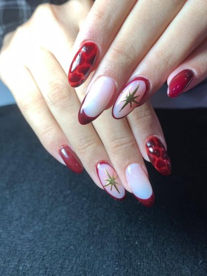 A mixed-design set in red, featuring a snakeskin pattern and a celestial star design on a French tip base.