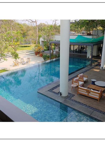 An overhead view of the expansive pool area at our Alibaug project. The design seamlessly integrates the deck, pool, and surrounding greenery to create a fluid and relaxing outdoor living space.