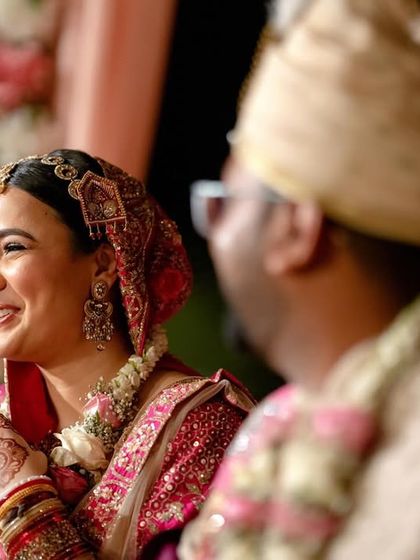 A candid shot of the bride's happy expression as she looks at her groom during the wedding rituals.