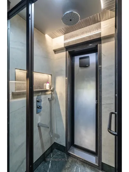 The shower area features a rain shower head and a sleek, modern design, continuing the bathroom's theme of understated luxury.