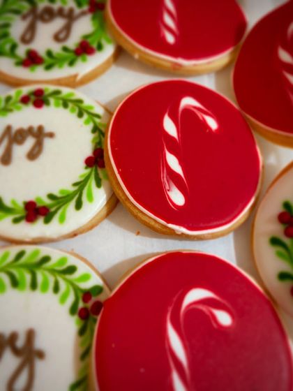 Our hand-decorated Christmas sugar cookies. These feature festive designs like candy canes and wreaths with the word "Joy," perfect for spreading holiday cheer.