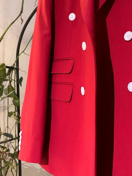 A detail shot of the red blazer, showing the ticket pocket and the quality of the fabric. Every element is considered in our bespoke designs.