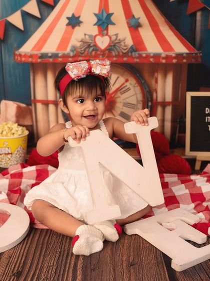 It's fun to be one under the big top! This vibrant carnival theme, with its classic red and white stripes, popcorn, and fun props, makes for an exciting first birthday shoot.