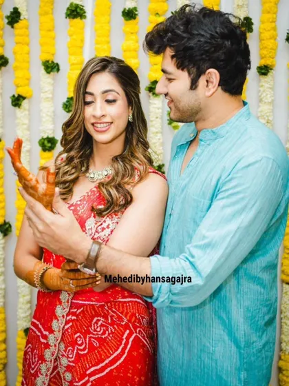 A candid shot of a couple at their pre-wedding function. Her hair is styled in soft waves with a simple twist, perfect for the happy occasion.