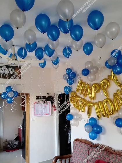 A simple room decoration with blue and silver balloons floating on the ceiling.