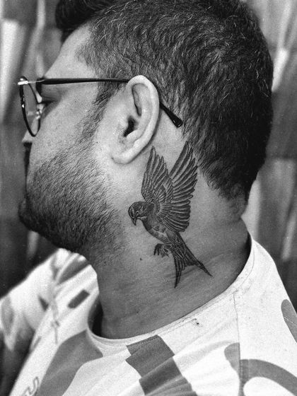 A black and white version of the swallow bird neck tattoo, highlighting the clean lines and smooth shading of the piece.