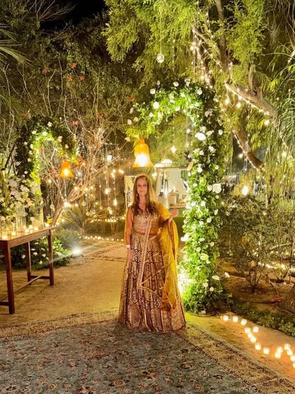 The same client at the beautifully decorated wedding venue. Our rental lehenga fits right in with the magical, fairy-light ambiance.