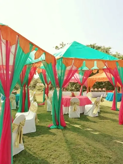 Colorful canopies in green, pink, and orange set up on a lawn for a daytime mehndi or sangeet event, providing shaded seating for guests.