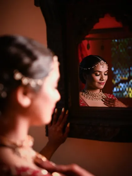 A bride's reflection in a mirror as she gets ready. This artistic shot from a Keralite wedding captures a moment of quiet anticipation before the ceremony begins.