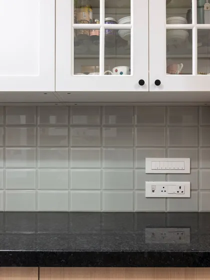 A close-up of the classic subway tiles and glass-fronted cabinets. This combination is timeless, allowing the beautiful crockery inside to become part of the kitchen's decor.