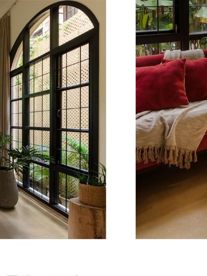 A closer look at the living area, where the deep red sofa provides a bold splash of color against the neutral walls and large windows looking out onto the garden.