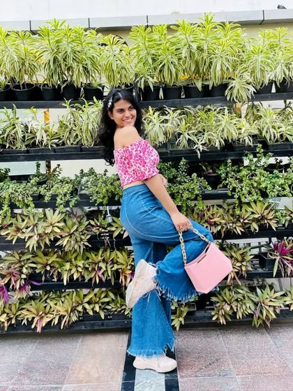 A cute and casual outfit featuring a pink floral off-shoulder crop top and wide-leg, frayed-hem jeans. The pink chain-strap bag ties the whole look together.