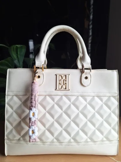 Our daisy keychain in a delicate light pink, offering a subtle and sweet floral accent for any bag.