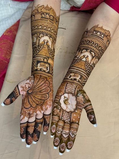 A stunning bridal design with a peacock feather on one palm and a floral motif on the other. The arms are adorned with palace scenes and peacocks.
