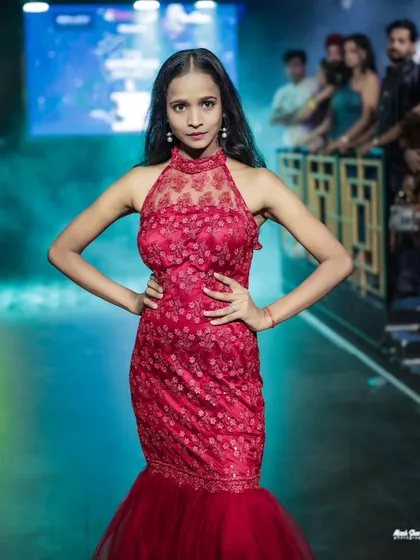 A close-up shot of the model in the red gown, focusing on the detailed neckline and her direct, confident gaze.