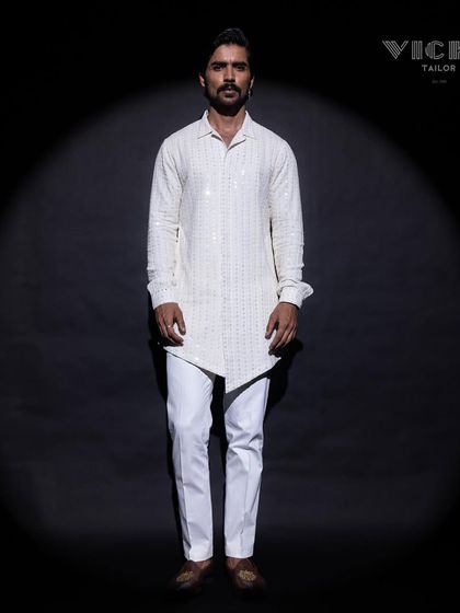 An asymmetrical white kurta with a unique texture. This piece, captured under a spotlight, highlights our commitment to creating versatile and stylish menswear.
