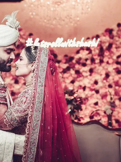 A romantic portrait of the couple in front of their custom wedding hashtag sign.