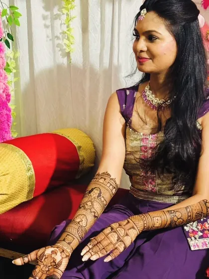 A client looking regal at her mehandi ceremony, her intricate henna complementing her traditional attire.