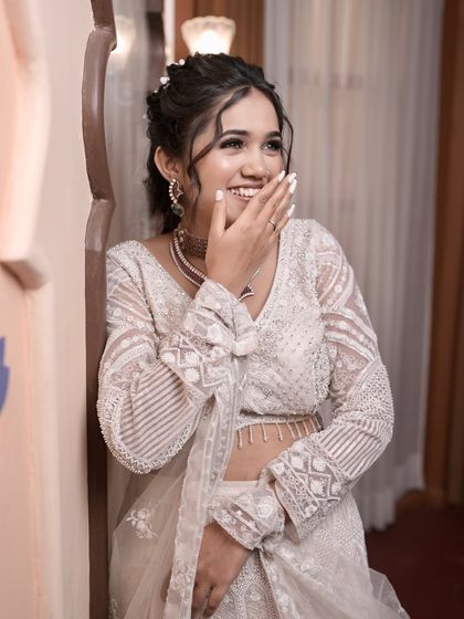 A candid moment showing the complete engagement look. You can see how the simple white nails on her hand complement her outfit and jewellery perfectly. This is a great example of a chic and understated style for pre-wedding functions.
