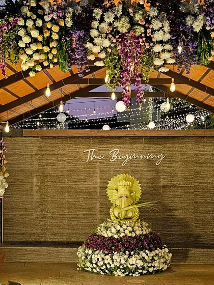 We create divine centerpieces that become the heart of your event. This beautiful Ganesha idol is meticulously crafted from flowers, set against a rustic backdrop and framed by lush floral arrangements, signifying a blessed beginning.