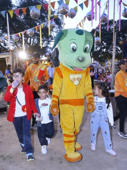 Tinga Dojo leads the way for an outdoor adventure, walking with a group of excited children through the festive grounds at Punjabi Bagh.