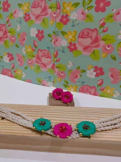This boho-style choker is made with embroidered flower motifs and a braided cord. It's a delicate yet eye-catching piece that comes with matching stud earrings.