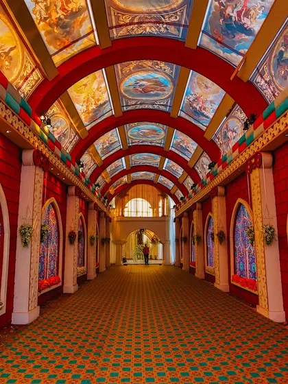 An incredibly detailed and artistic wedding entrance. The arched hallway features stained-glass style windows and a ceiling painted with Renaissance-style art, creating a truly unique and breathtaking experience.