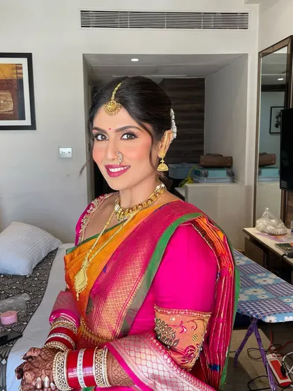 A complete South Indian bridal look. The hair is styled in a traditional braid with a gajra, perfectly complementing the vibrant Kanjeevaram saree and temple jewellery.