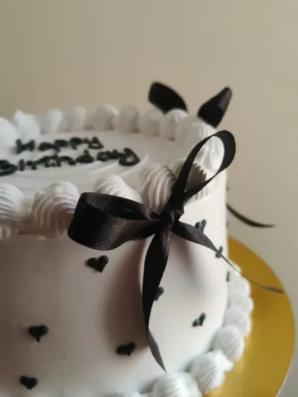 A close-up of the delicate black ribbon bow on this chic vintage cake.