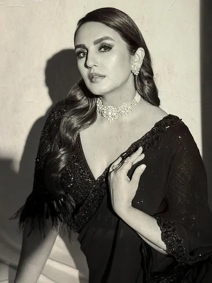 A black and white portrait of Huma Qureshi in her Nitika Gujral saree. This shot highlights the classic glamour and intricate details of her choker and earrings.