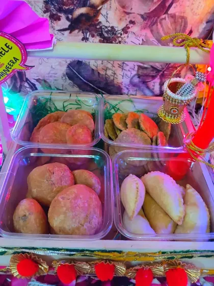 The complete Holi hamper with festive decorations, including water balloons and a 'Holi Khele Raghuveera' tag.