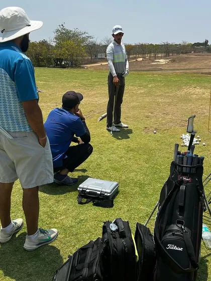 A team of coaches analyzing a player's swing on the range. Our collaborative approach means multiple expert eyes are on each player, using technology to find the best solutions.