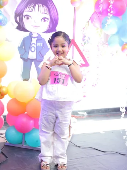 The birthday girl enjoying her 'Squid Game' themed party. I can provide themed cutouts and props that are kid-friendly and perfect for photos.