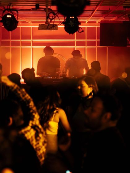 A silhouette of me and my partner DJ against a glowing red backdrop.