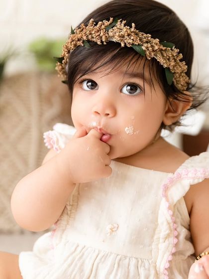 Another angle from the boho cake smash, focusing on the baby's curious expression as she enjoys her birthday treat.