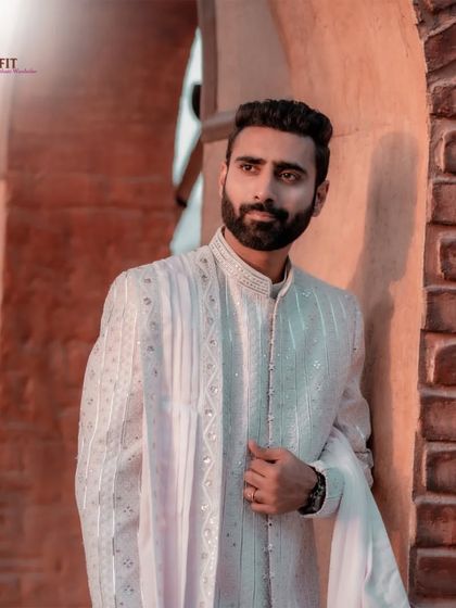 This custom-made sherwani in a light, textured fabric features vertical panels of embroidery and mirror work. It's paired with a matching dupatta for a clean and elegant groom's outfit.