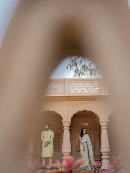 A creative shot taken through a latticed window, adding a layer of intrigue and artistry to this royal-themed couple portrait.